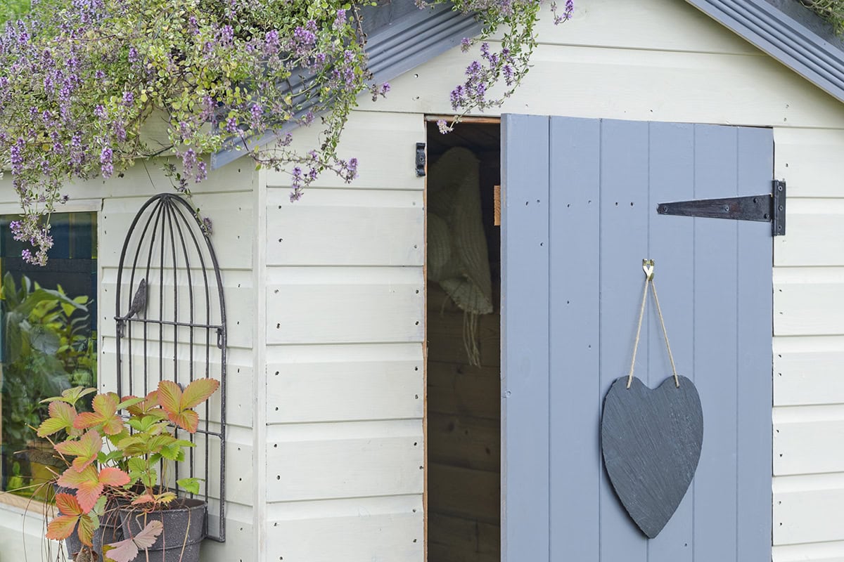 Een tuinhuis in wit rn blauw met een hart aan de deur