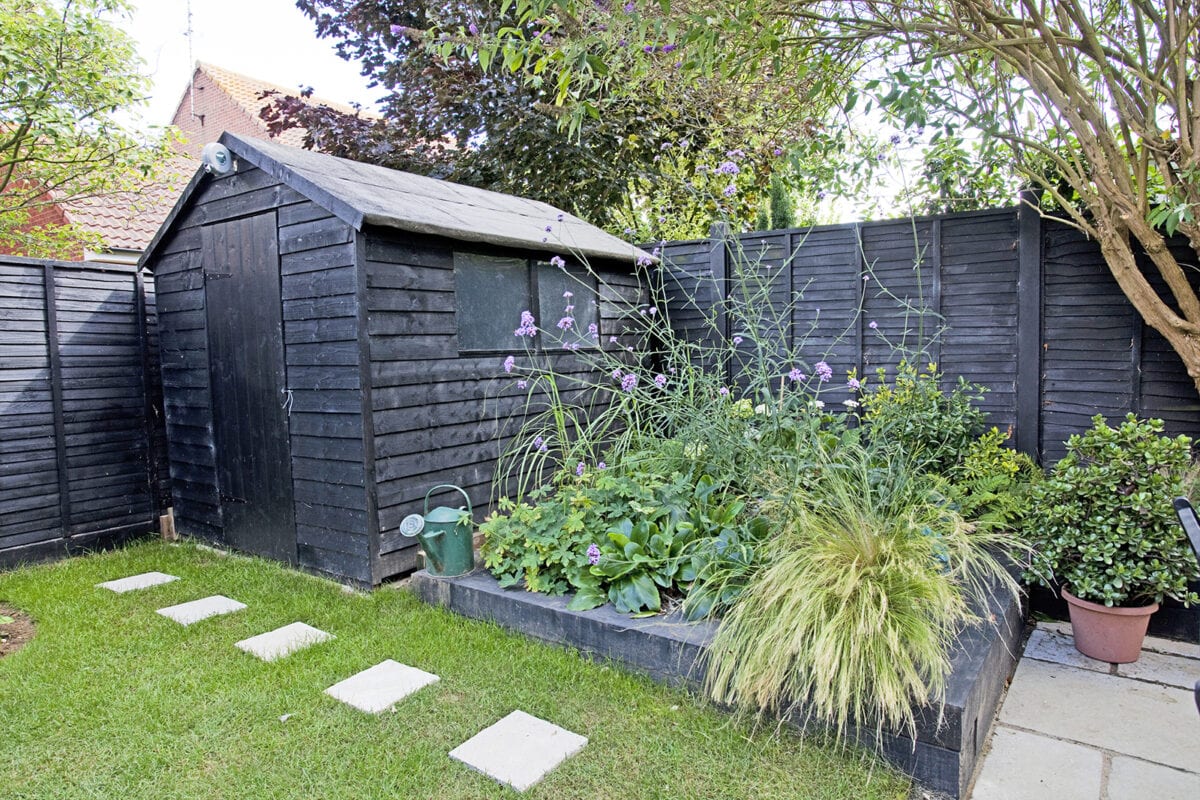 Een zwarte tuinhuis met dichte ramen en deuren