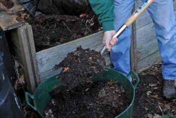 Persoon schept compost uit een compostbak in een grote teil.