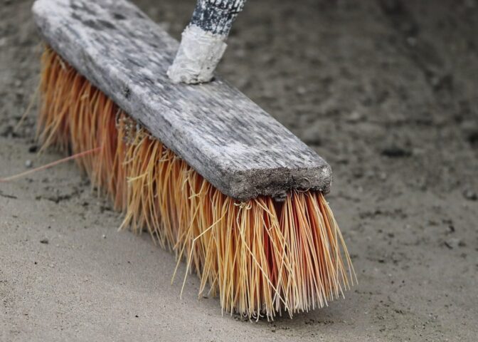Bezem en zand tegen groene aanslag