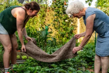Annelies en haar dochter leggen woldoek in de verhoogde tuinbedden.