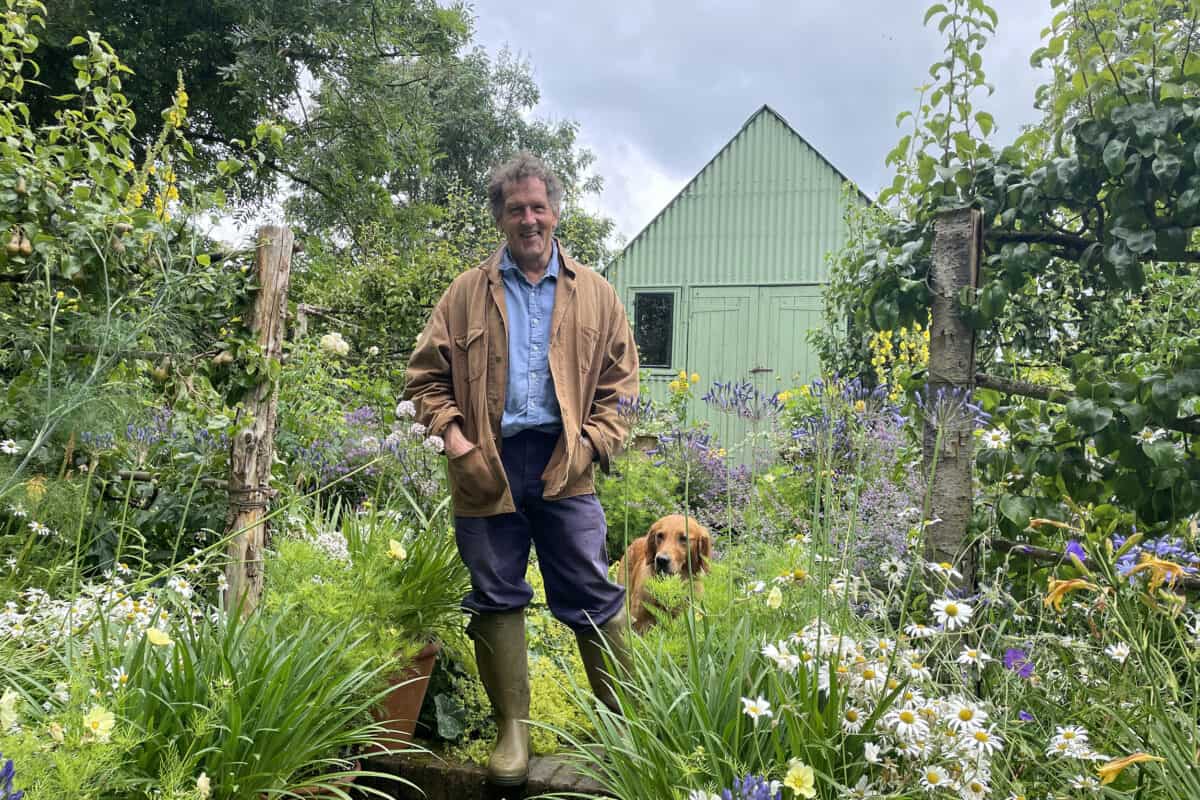 Monty Don en zijn hond Ned staan in de tuin vol bloemen in Longmeadow