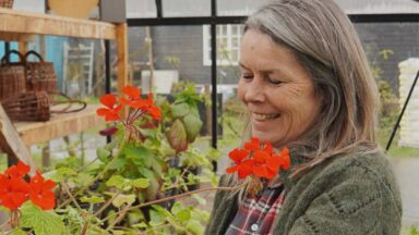 Jacqueline op de kwekerij met rode bloemen.