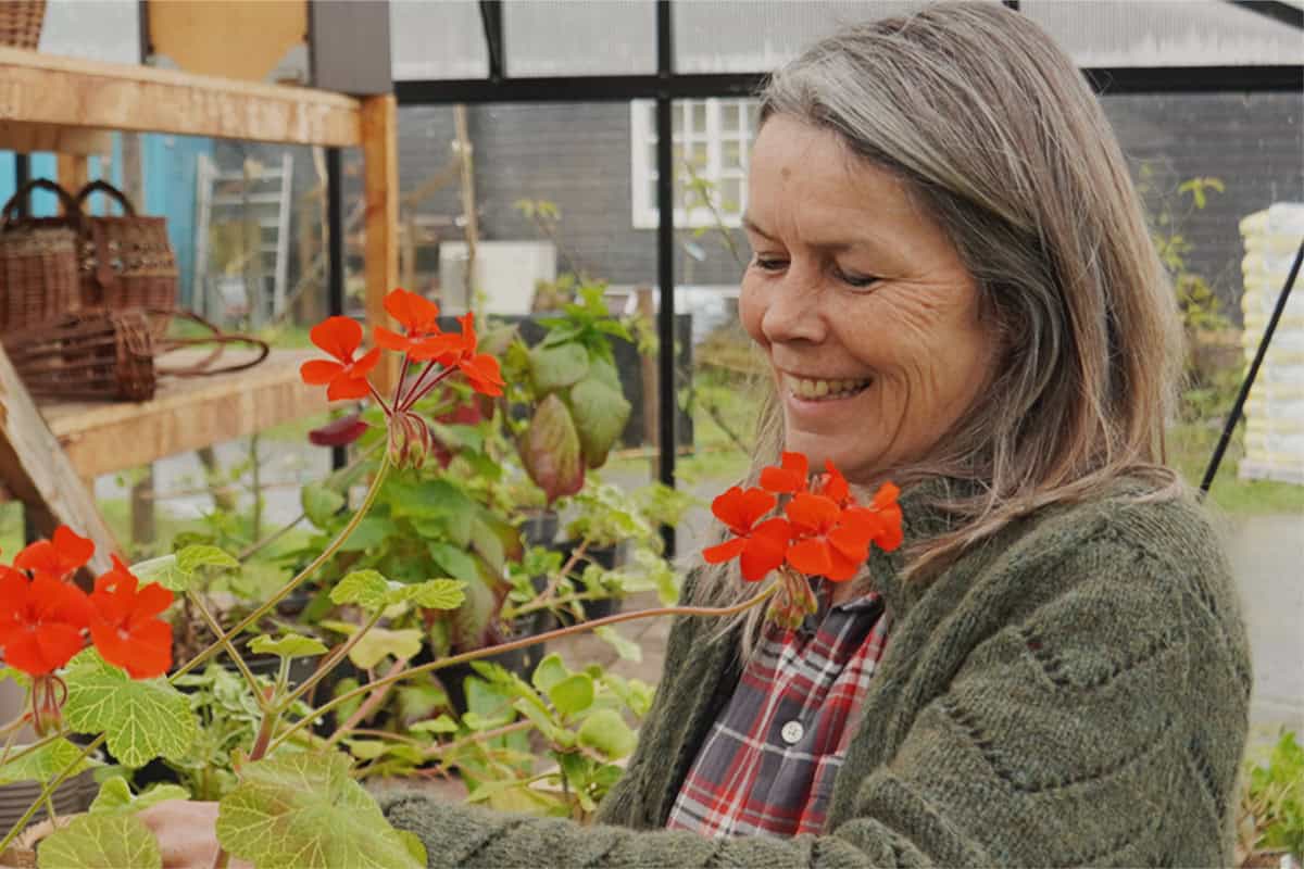 Jacqueline op de kwekerij met rode bloemen.