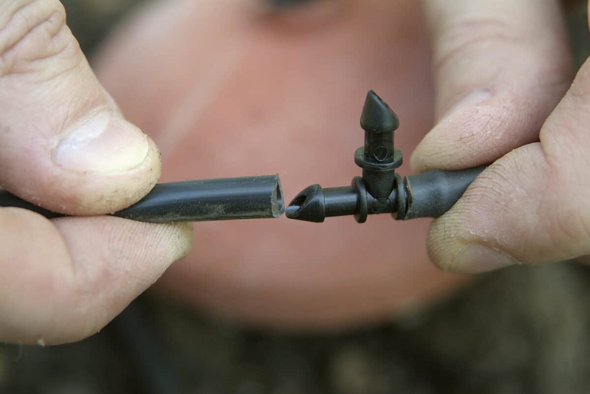 Iemand houdt een t-stukje vast van een druppelslang