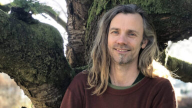 Jeroen van Mill poseert voor een boom.