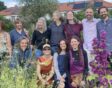 Groepsfoto van alle kwekers en medewerkers van kwekerij Noorderbloemen, tussen bloeiende planten.