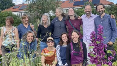 Groepsfoto van alle kwekers en medewerkers van kwekerij Noorderbloemen, tussen bloeiende planten.