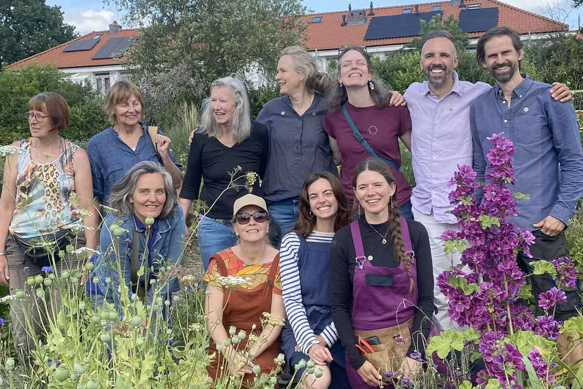 Groepsfoto van alle kwekers en medewerkers van kwekerij Noorderbloemen, tussen bloeiende planten.