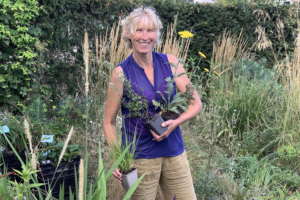 Saskia poseert op haar kwekerij met planten.