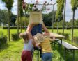 Twee kinderen spelen met de kweker met bloemen voor het gezicht.