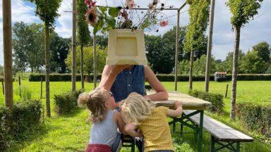 Twee kinderen spelen met de kweker met bloemen voor het gezicht.