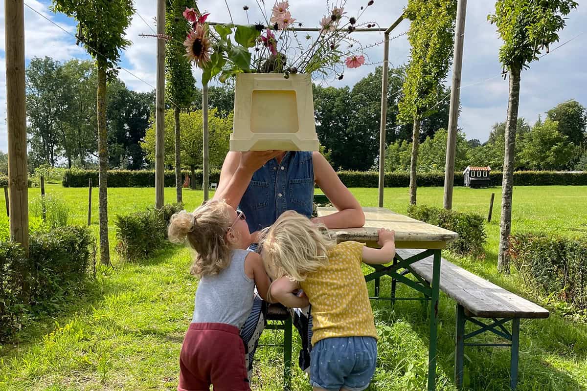 Twee kinderen spelen met de kweker met bloemen voor het gezicht.