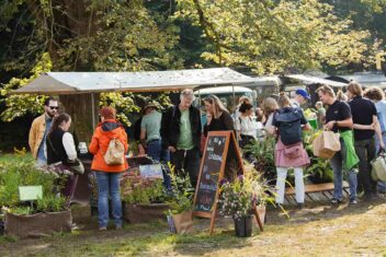 Mensen bij kraam vol bloemen op de ambachtelijke plantenmarkt