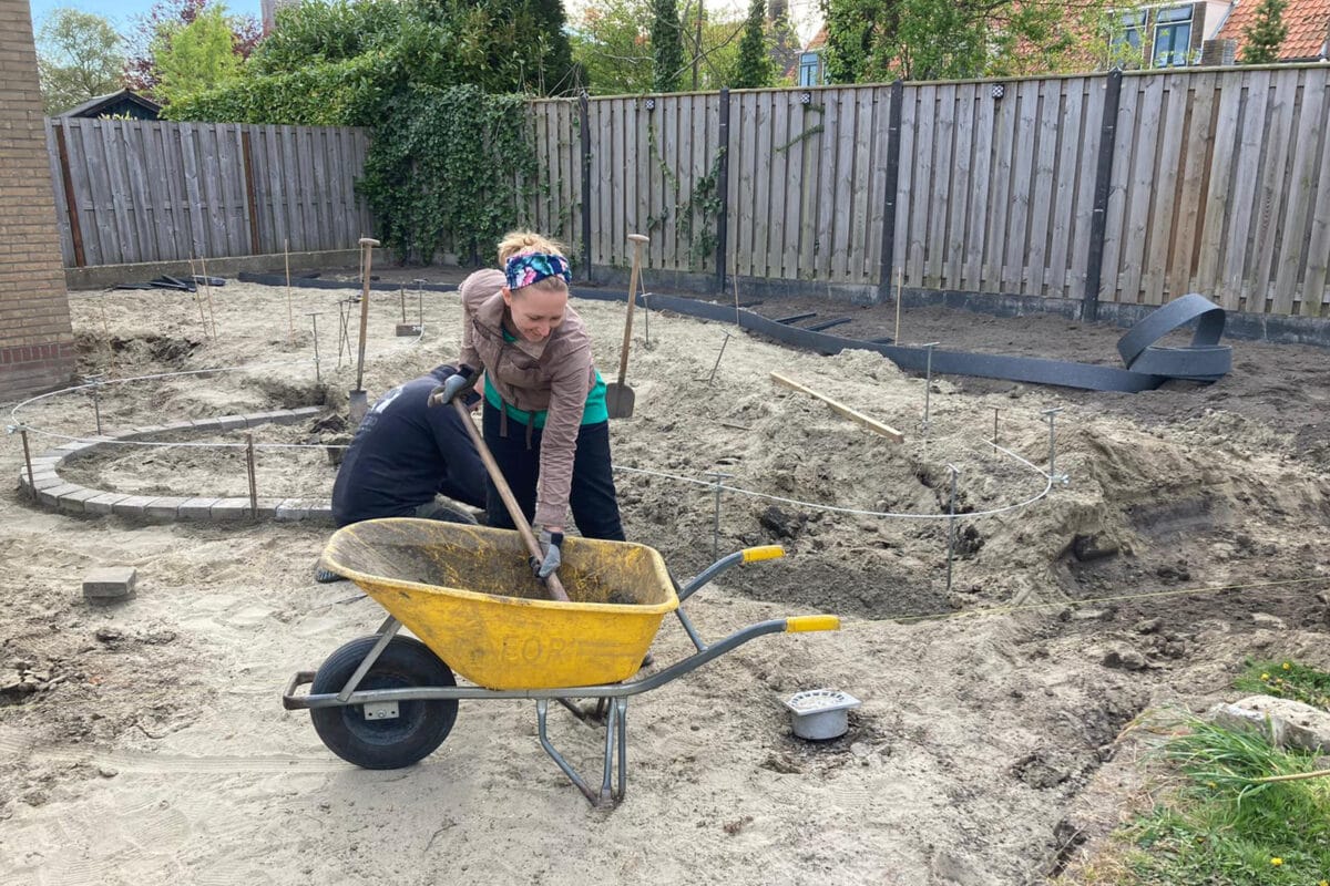 Met een kruiswagen en veel zand wordt de tuin van Miranda gerenoveerd.