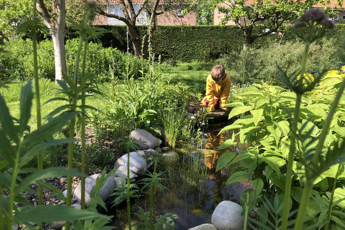 Kind kijkt in salamanderpoep en linksachter zie je een bloemenheuvel.