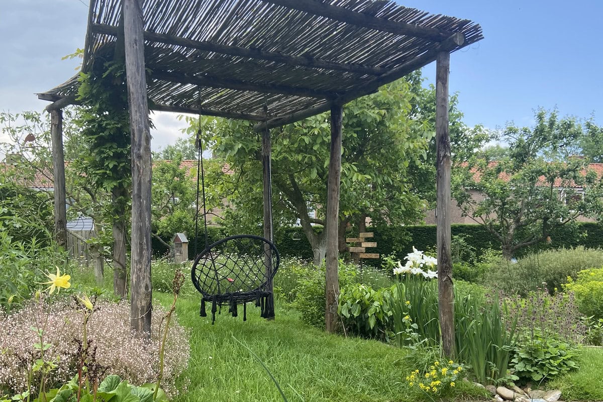 Een houten pergola in de zonnige tuin van Miranda Engels.