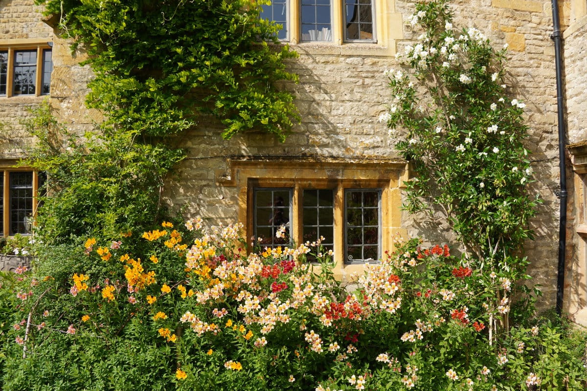 Een close-up van het landhuis omringd door bloemen bij Upton Wold.