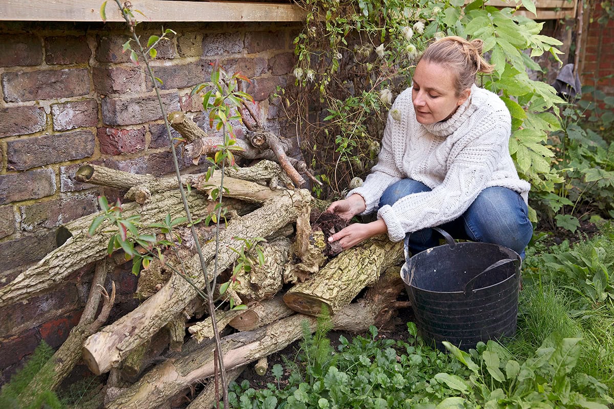 vrouw legt bladeren tussen takkenstapel