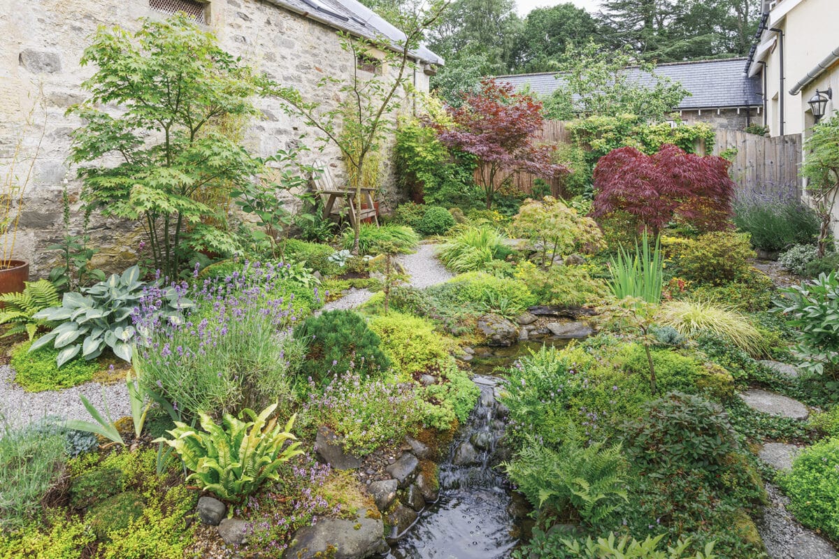 Een grindtuin met planten zoals een acer, en waterpartijen.