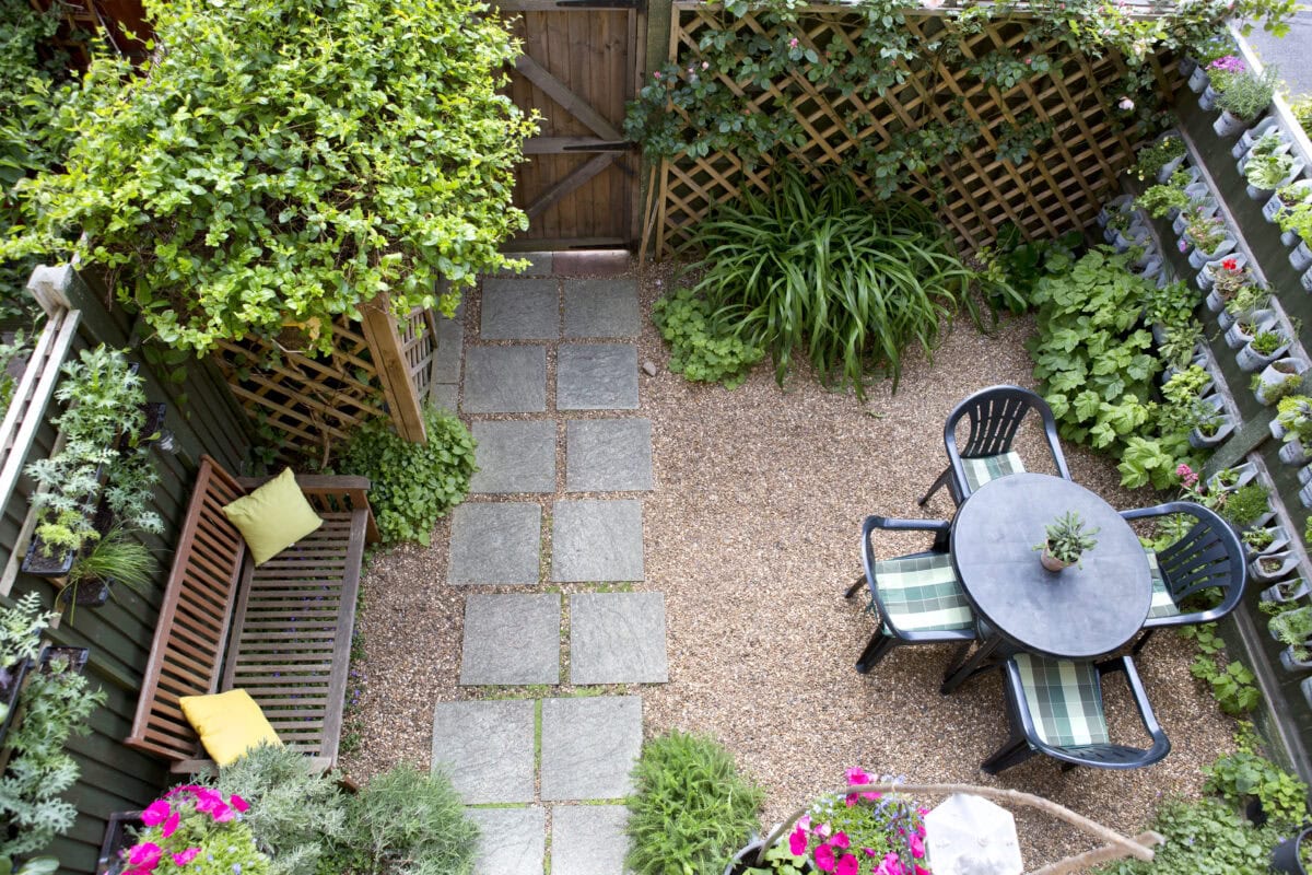 Tuin van bovenaf met grind, een rustiek pad en een zitje.