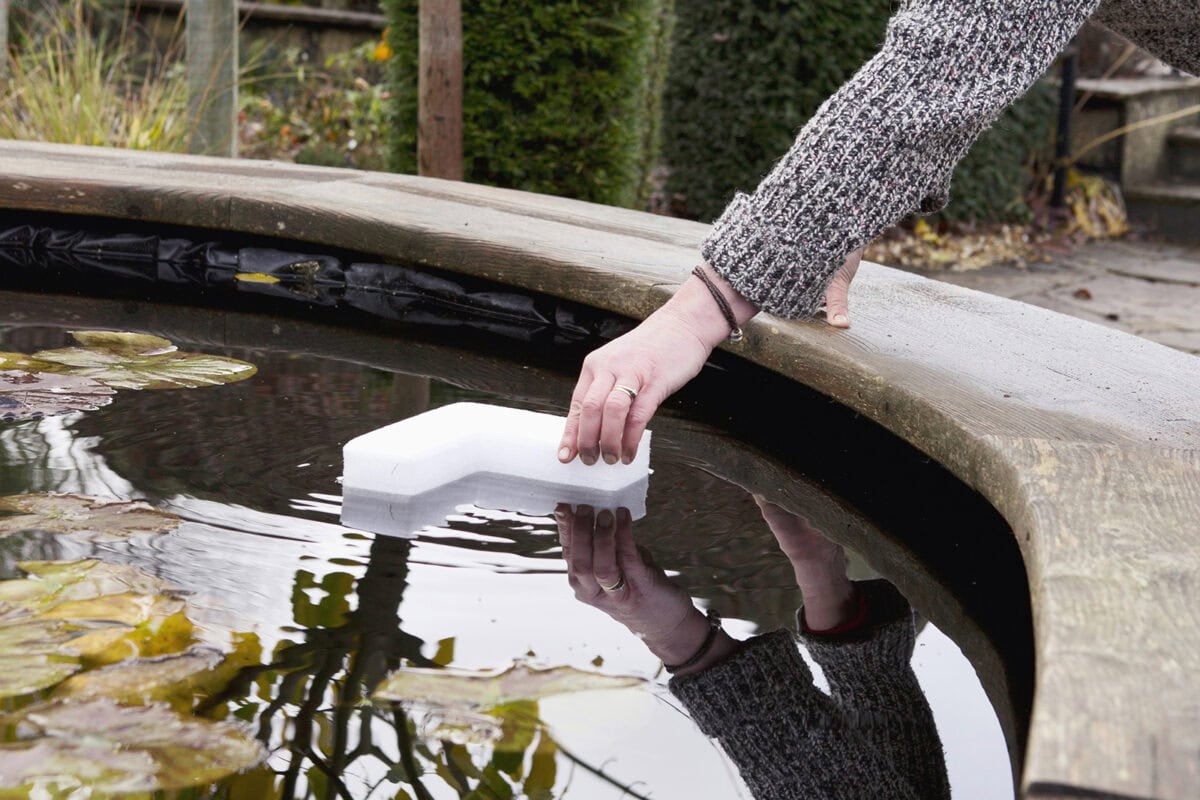 Iemand legt piepschuim in de vijver om te voorkomen dat hij bevriest.