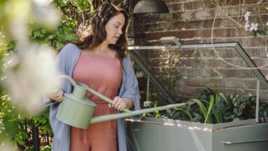 Anne geeft moestuinplanten in een kweekkas water met een gieter
