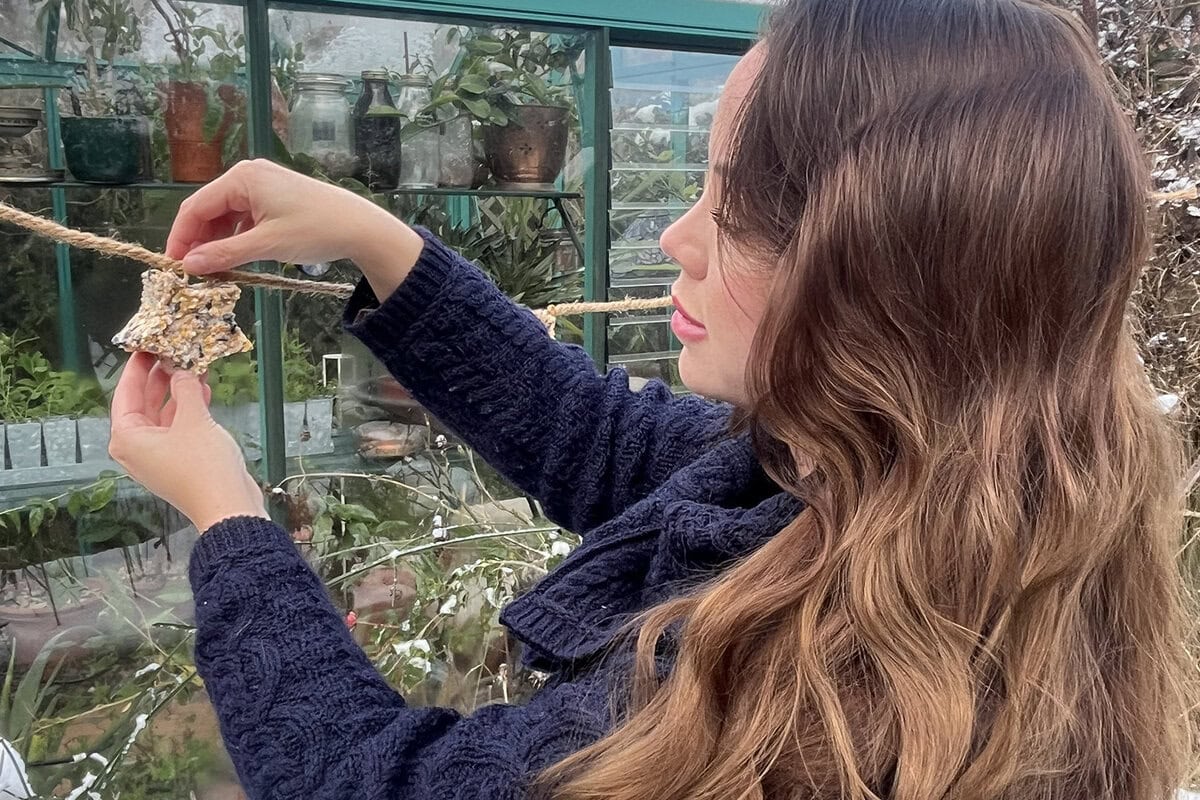 Anne Wieggers hangt een vogelslinger op in haar tuin.