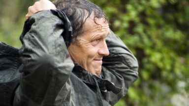 Tuinexpert Monty Don trekt zijn regenjas aan in de tuin.