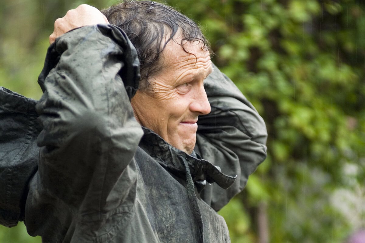Tuinexpert Monty Don trekt zijn regenjas aan in de tuin.