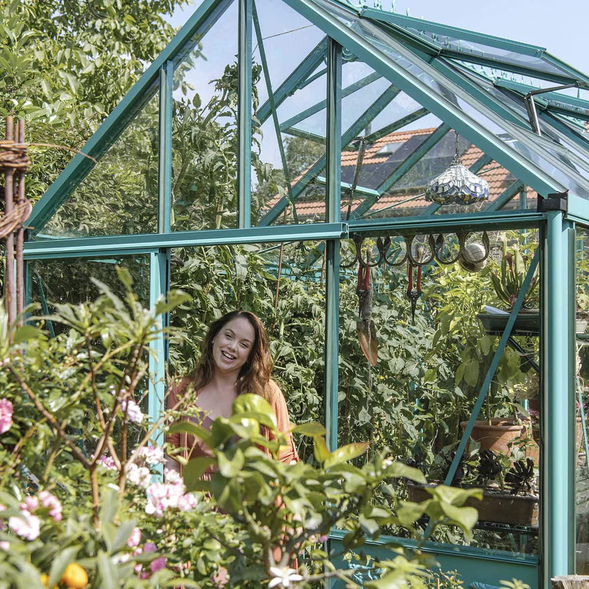 Anne staat voor haar kas in de zon.