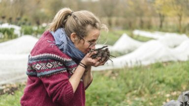 Esther houdt handen vol bokashicompost dichtbij haar gezicht om de geur te ruiken.