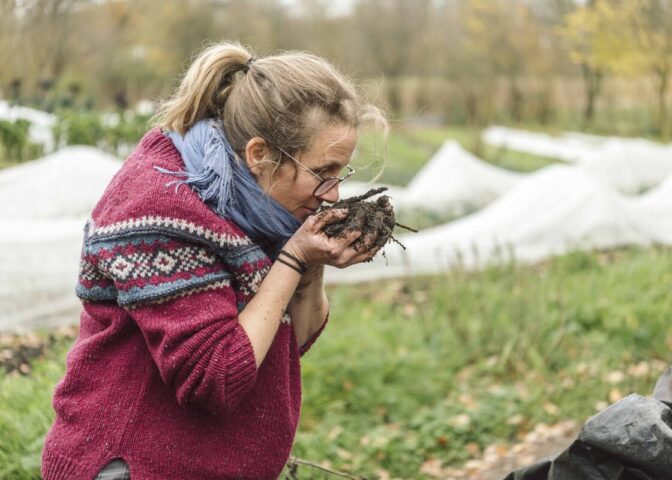 Esther houdt handen vol bokashicompost dichtbij haar gezicht om de geur te ruiken.