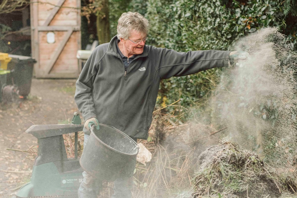 Tuinier Lambert voegt mineralen toe aan de bokashihoop.
