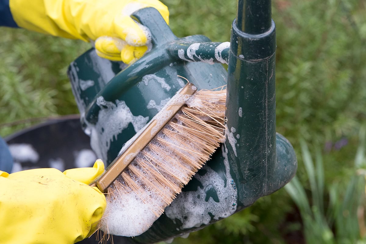 Gieter wordt schoongemaakt met borstel en zeep