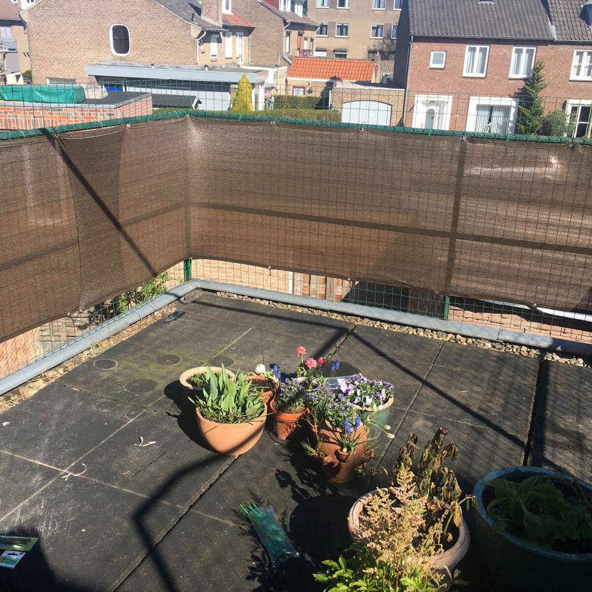 Een kaal dakterras met tegels en een paar potten.