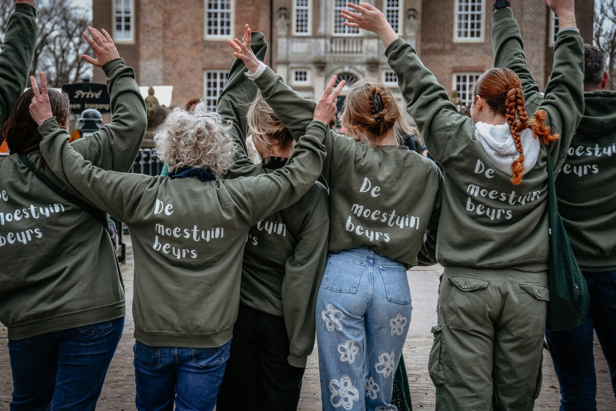 Mesewerkers van de Moestuinbeurs met een groene Moestuinbeurstrui aan, juichend.