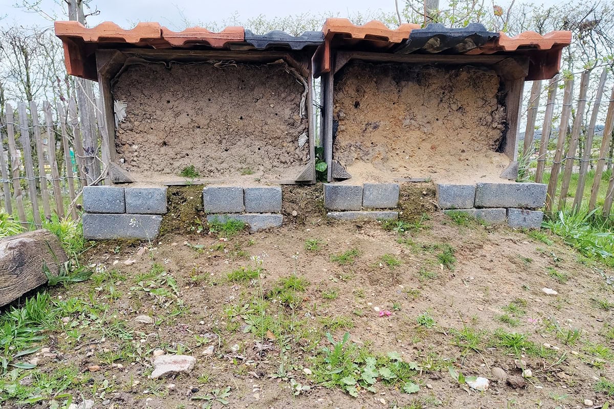 Twee houten kisten met leem op hun kant met afdak erboven