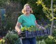 Giny de Jong houdt een tray met planten vast in de tuin.