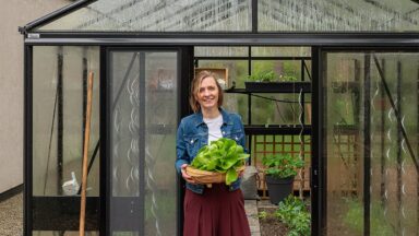 Joke voor de ingang van haar serre met een oogstmand in de handen.