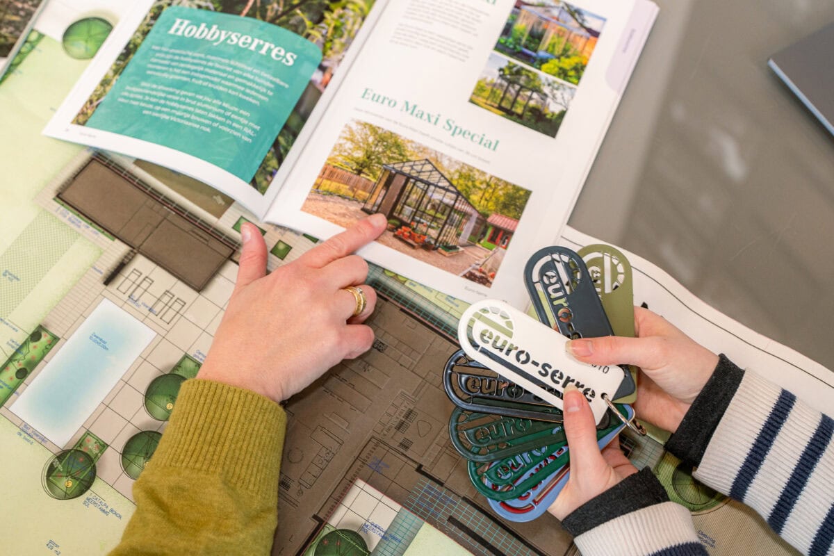 Handen wijzen iets aan in een catalogus, andere handen houden kleurstalen vast.