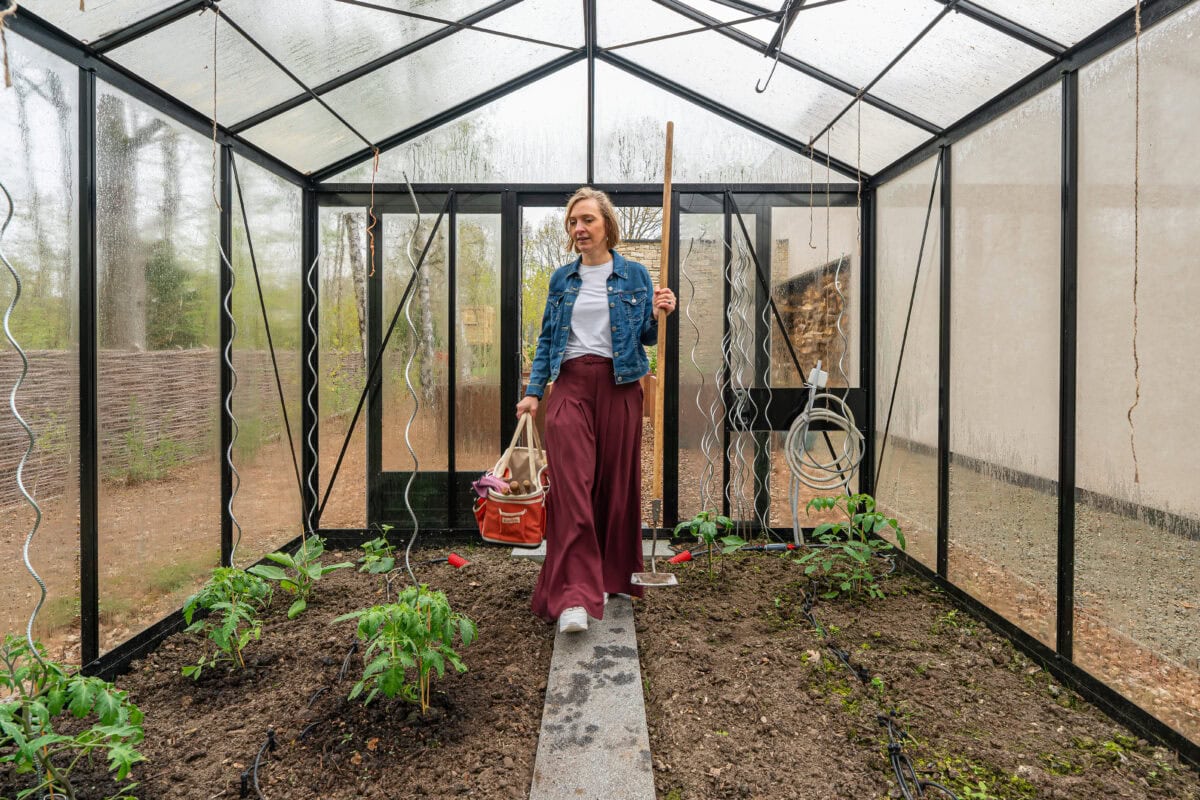 Joke loopt de serre in met gereedschappen.