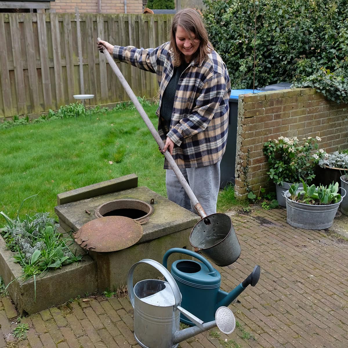 Hester vult gieters met water uit de oude put.