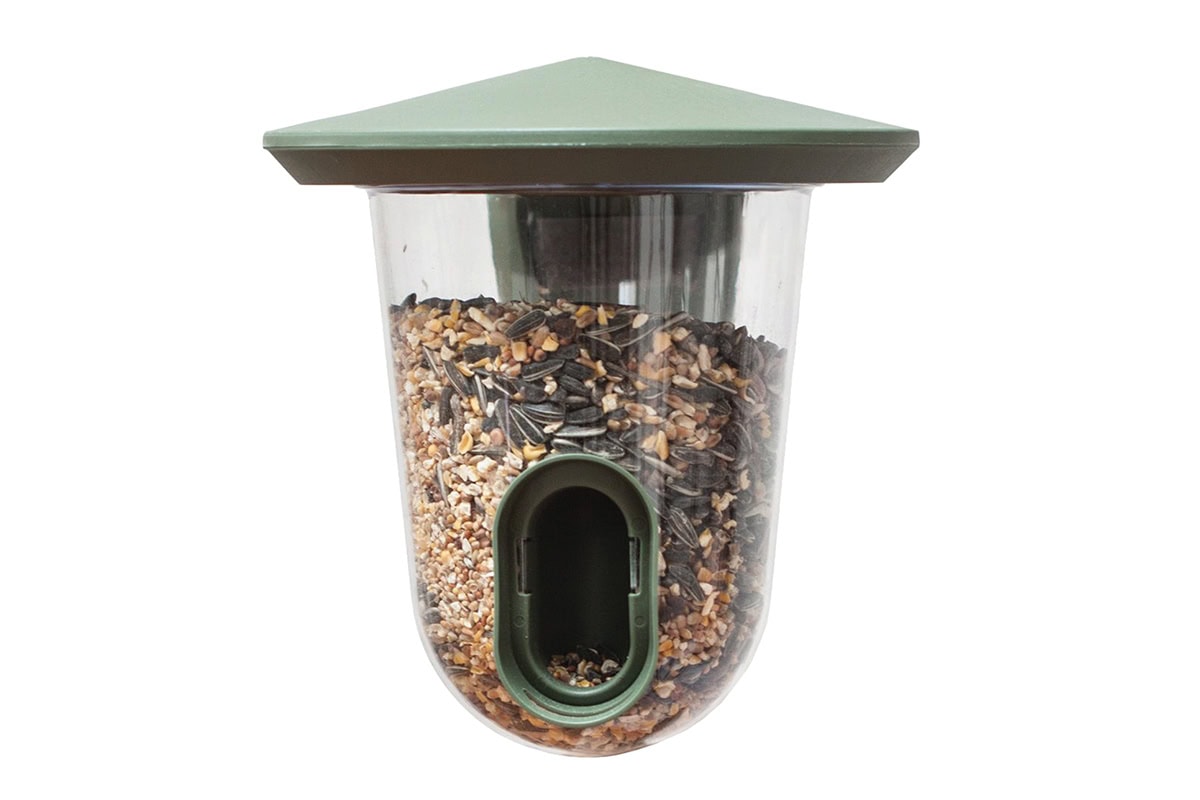 Voedersilo voor vogels met een groen dakje en zaad erin.
