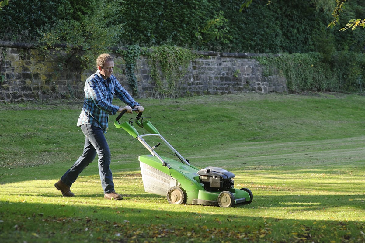 Man maait het gras met een handgrasmaaier.