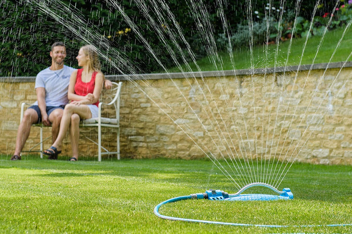 Een zwenksproeier op het gazon, met waterstralen