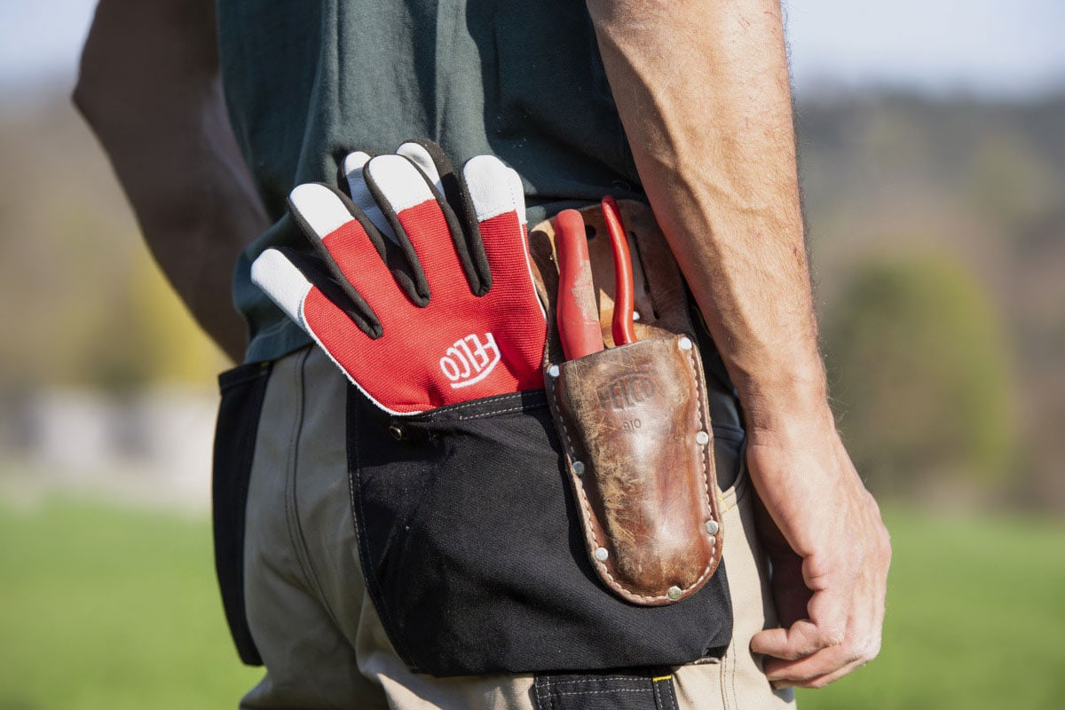 Man met Felco-handschoenen en snoeischaar in een holster.