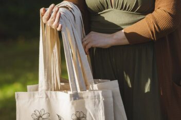 Vrouw houdt een aantal linnen tasjes in haar hand.