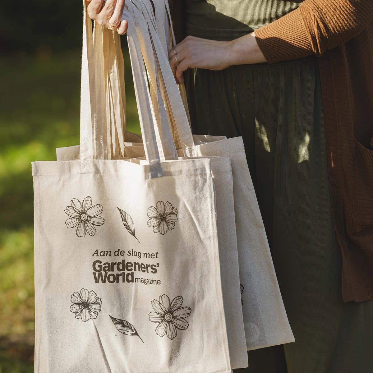 Vrouw draagt linnen tasjes met daarop: aan de slag met Gardeners' World.