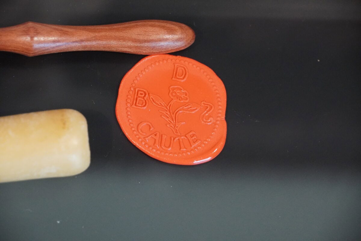 Oranje was met daarin gedrukt het zegel van Benedictus de Spinoza met onder andere een roos.
